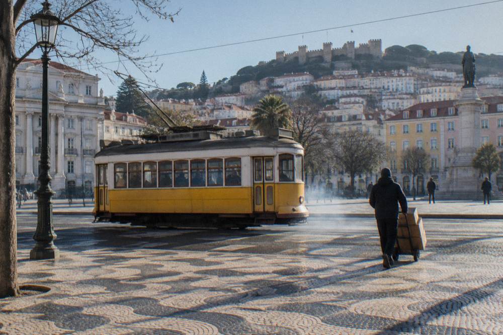 Yellow historic tram on a Lisbon street with hills in the background