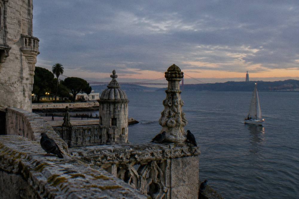 Sailboat passing the Belem Tower on the Tagus river at dusk