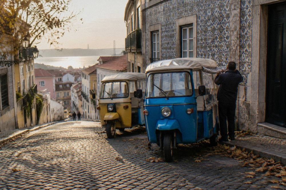 Colorful tuk tuks parked on a sloped street beside tiled buildings