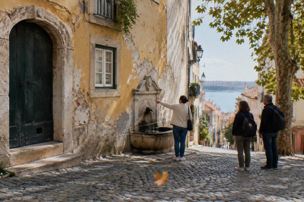 Small group of visitors listening to a guide beside an old Lisbon doorway
