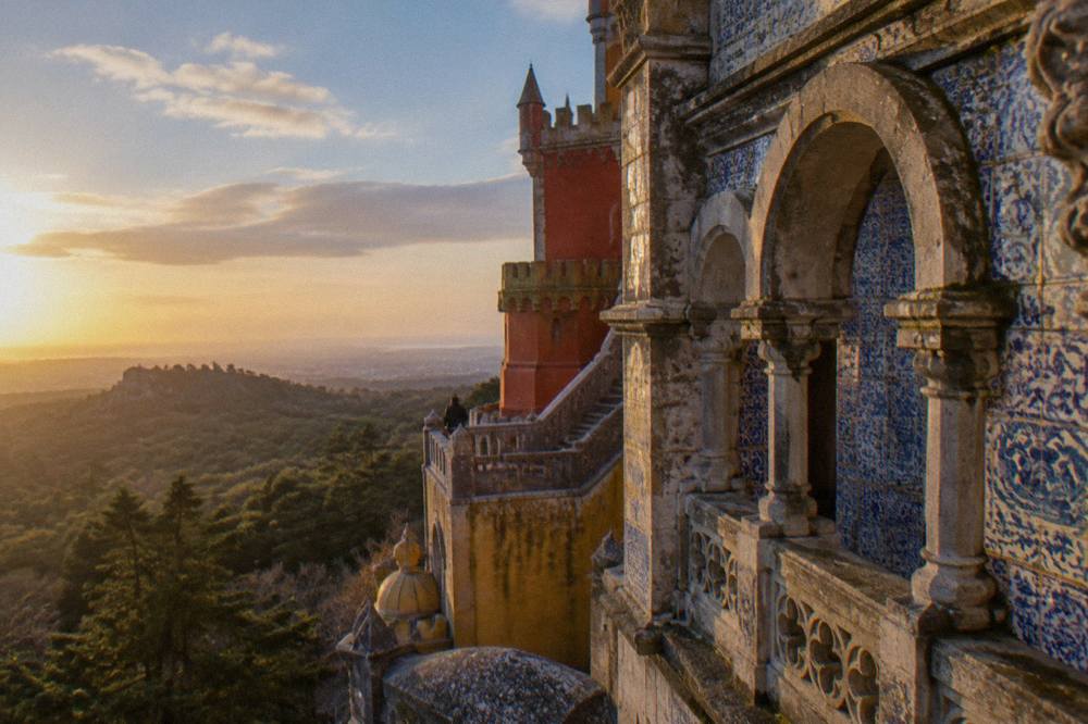 Ornate terracotta facade of the Pena Palace with carved arches and patterned tilework above the forest canopy