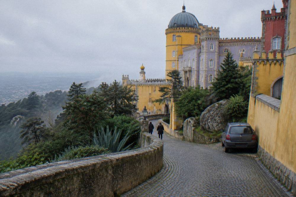 Winding cobbled street in Sintra town centre lined with pastel buildings and parked cars