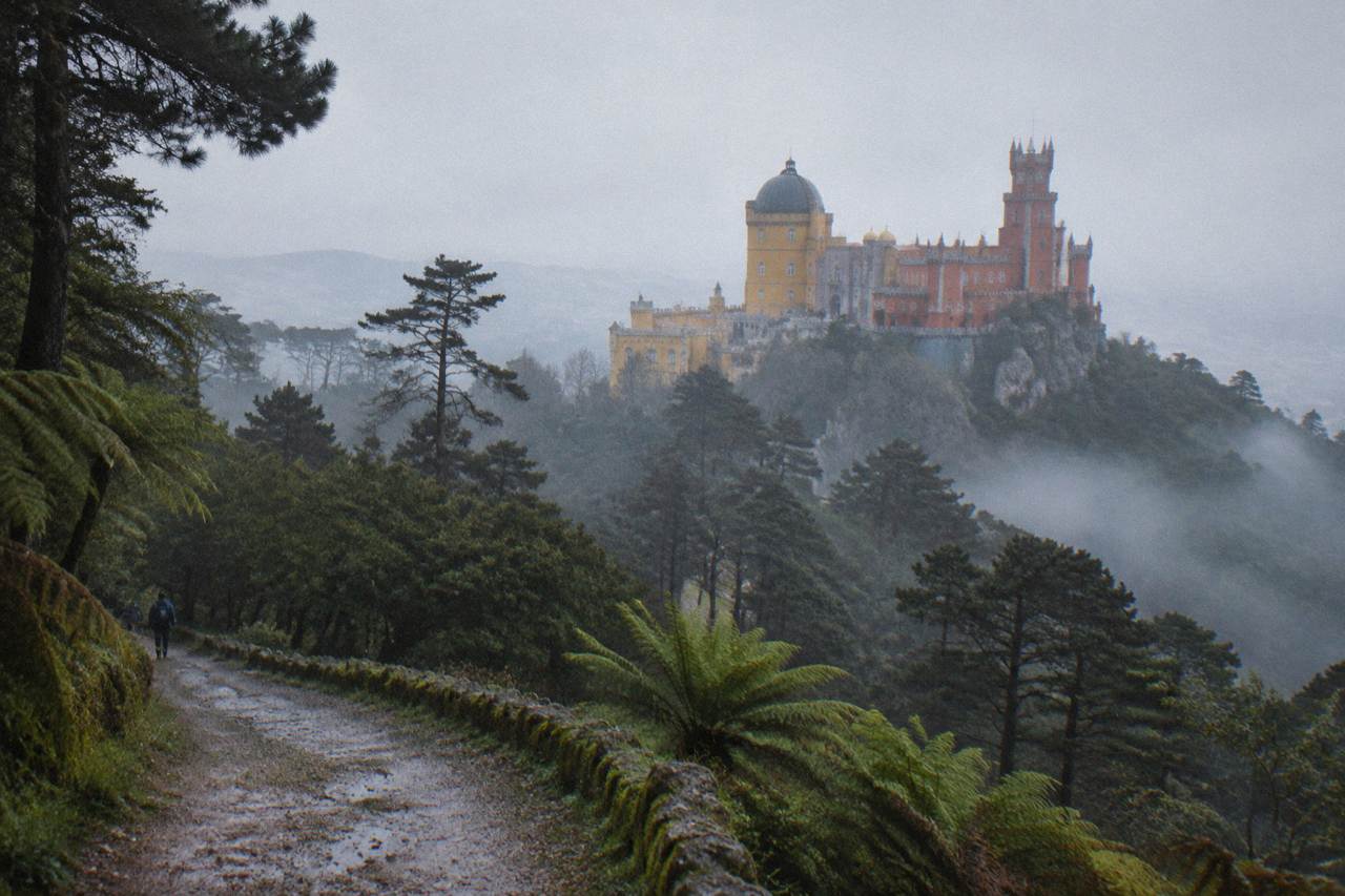 Terraced hills of Sintra with the Pena Palace rising above the tree line under a hazy sky