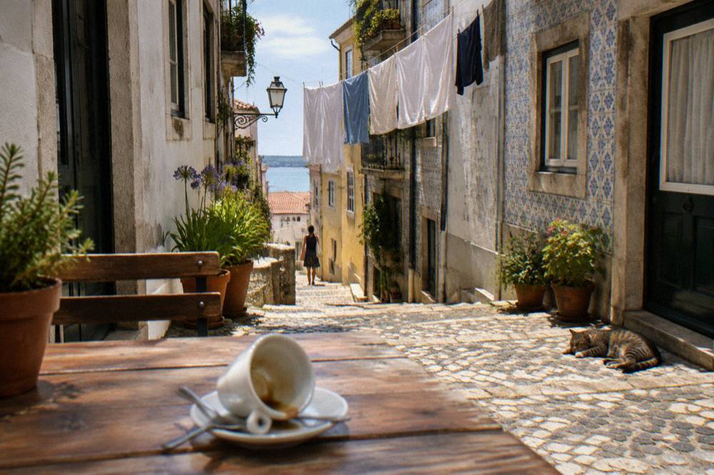 A narrow Alfama street with café tables and laundry overhead