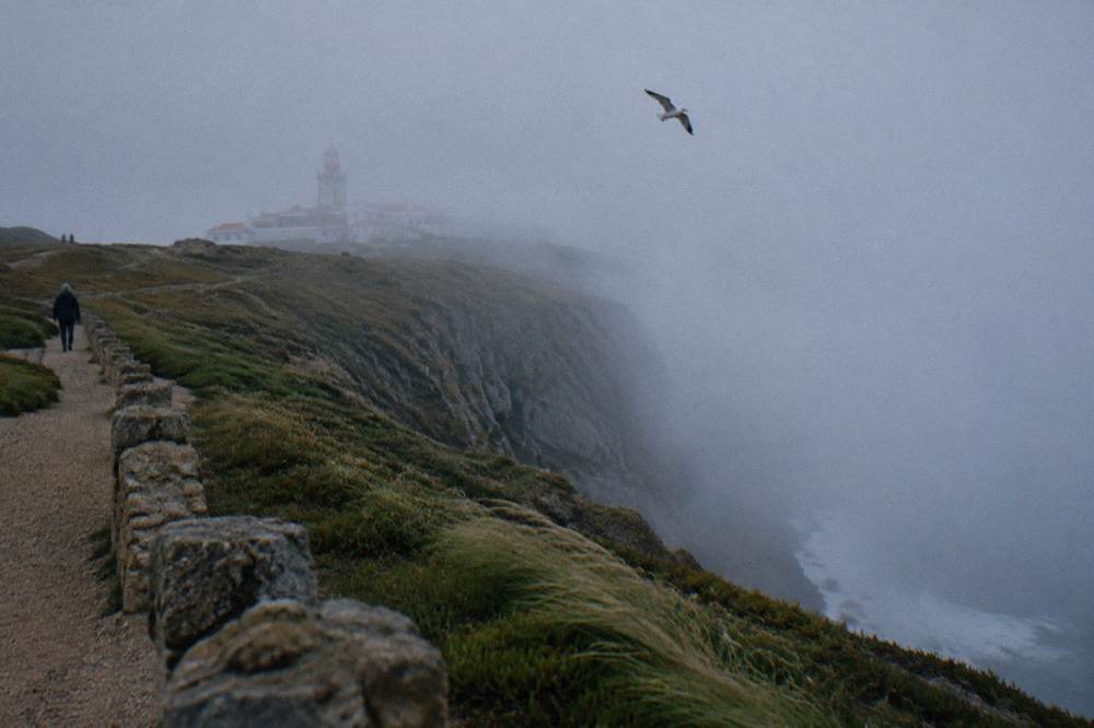Cliffs at Cabo da Roca above the Atlantic Ocean with a lighthouse in the distance