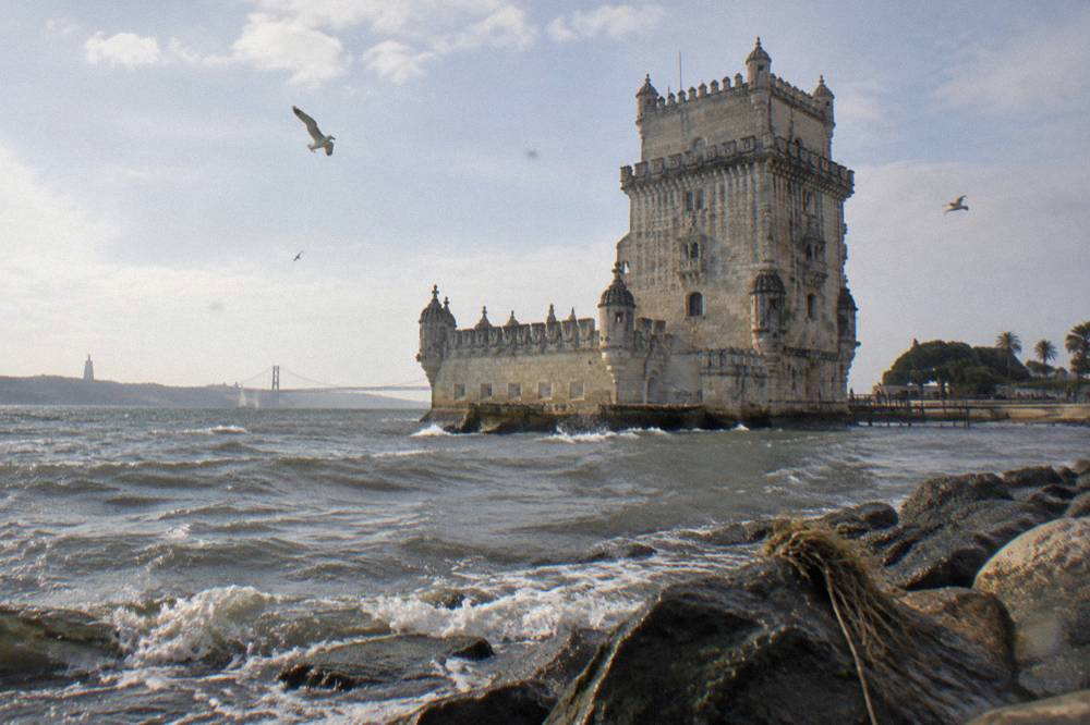 Belém Tower standing at the water's edge with its crenellated terrace and river beyond