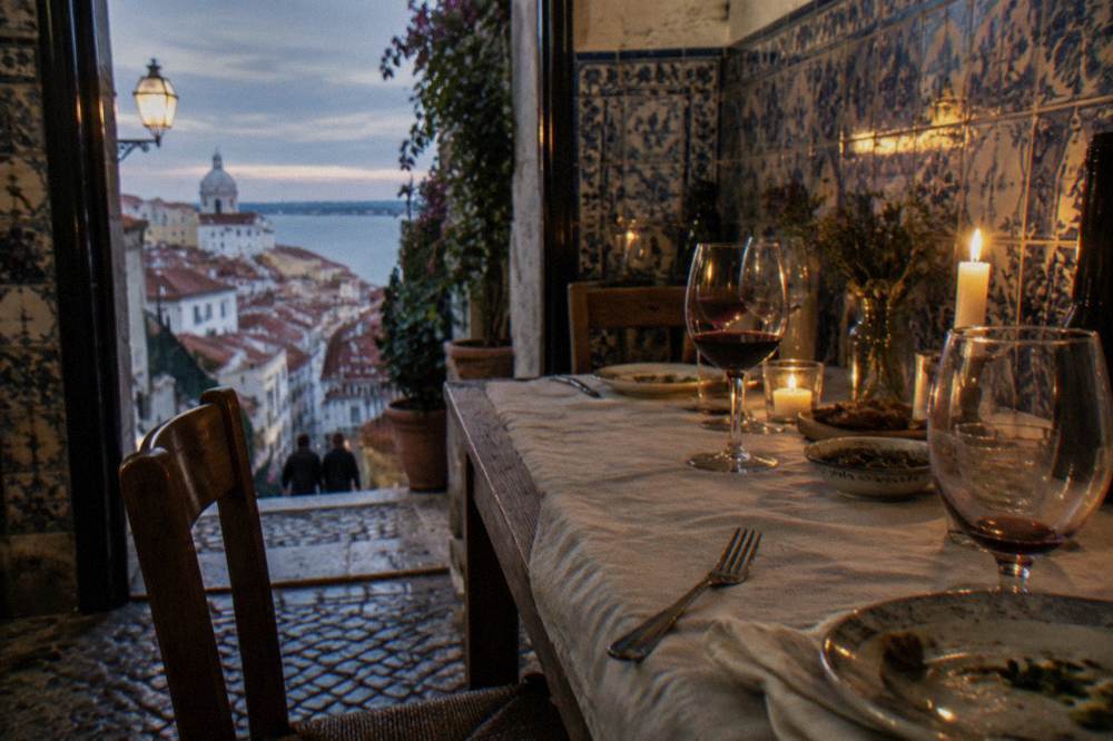 Set table with candles and wine glasses ready for an evening fado dinner in a tiled room