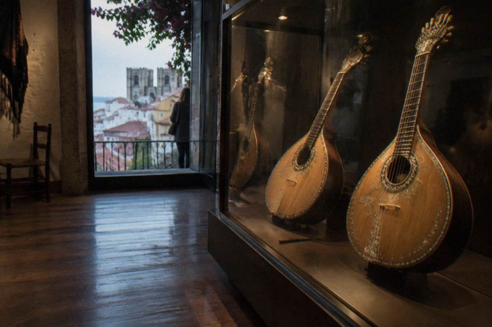 Exhibit of historic fado guitars and portraits inside a museum gallery