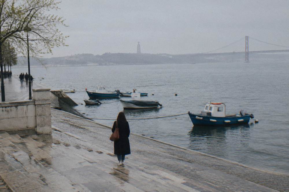 Wet stone steps at Cais do Sodre leading down to moored boats on the hazy Tagus riverfront in Lisbon