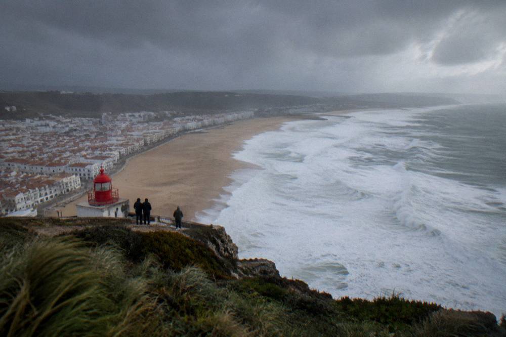 A coastal town seen from a high clifftop viewpoint with a wide sandy beach below