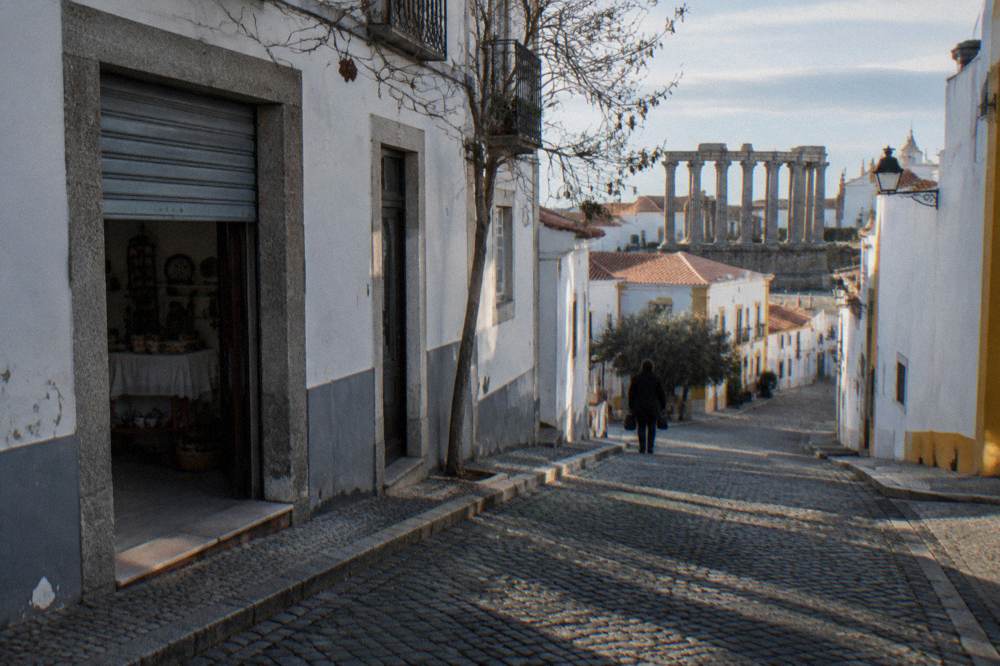 Whitewashed Evora street with the Roman temple columns visible beyond rooftops