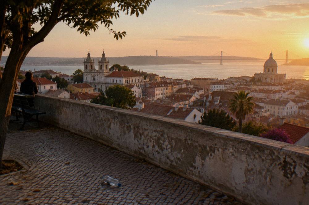 Panoramic view across Lisbon rooftops and church towers at golden light from a hilltop terrace