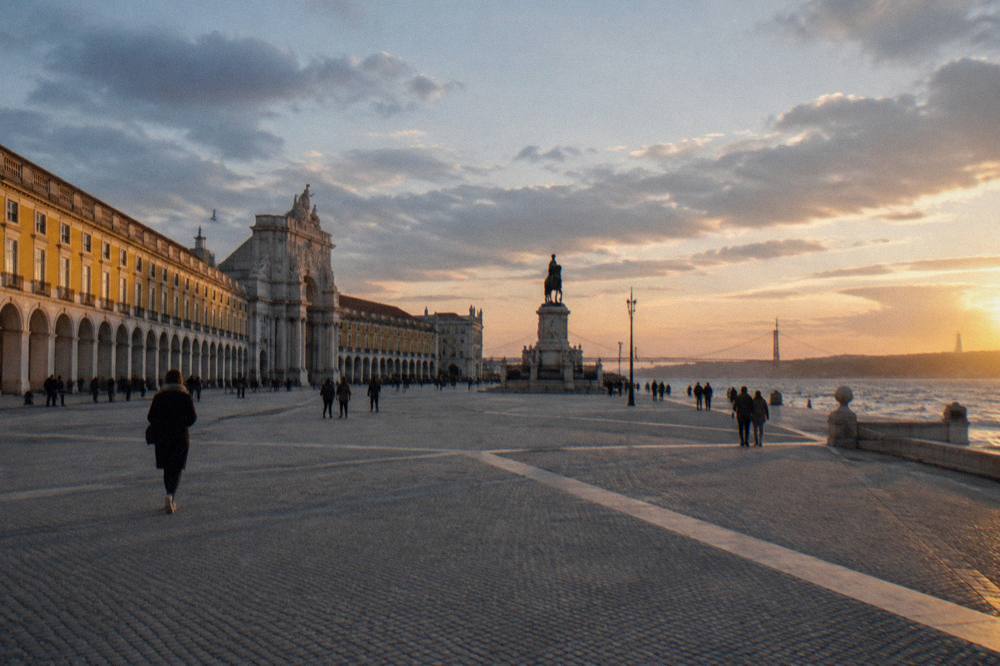 Wide square beside the river with arcaded yellow buildings and an open promenade