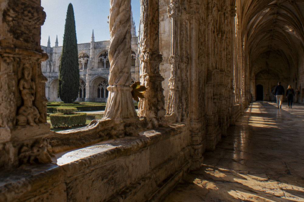 Cloisters of the Jeronimos Monastery with stone arches in warm light