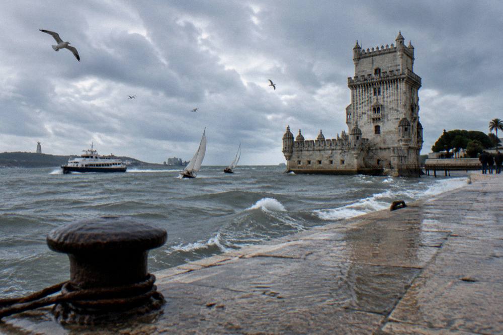 Sailboats and ferry on the Tagus river seen from a Lisbon embankment
