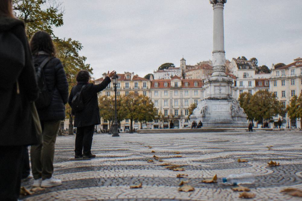 Guide speaking to a small group in a Lisbon square beside old building facades