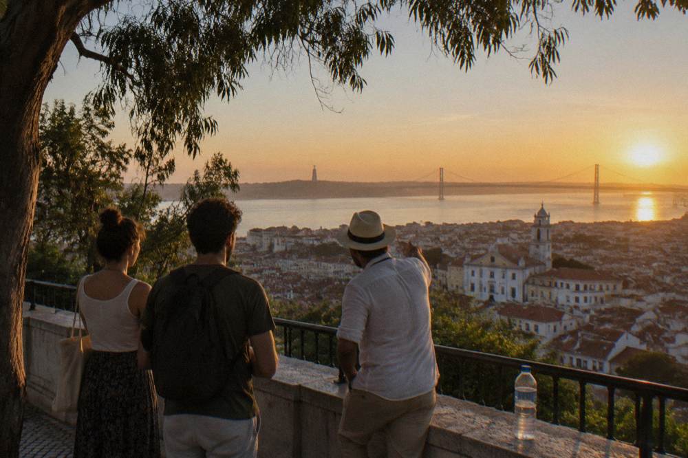 Private guide leading two visitors along a Lisbon viewpoint terrace overlooking the river