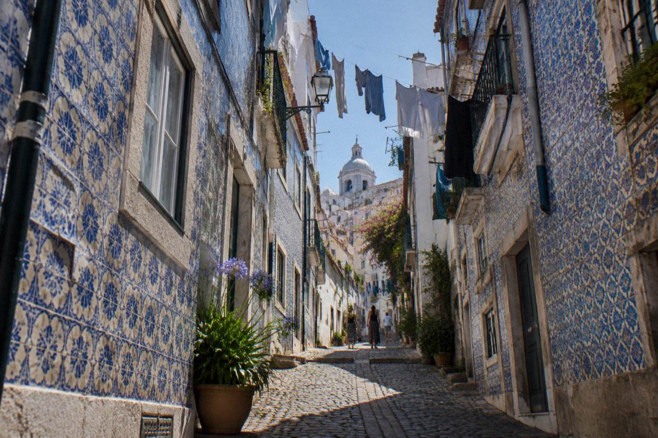 Narrow Alfama street with tiled building facades rising over the old town rooftops