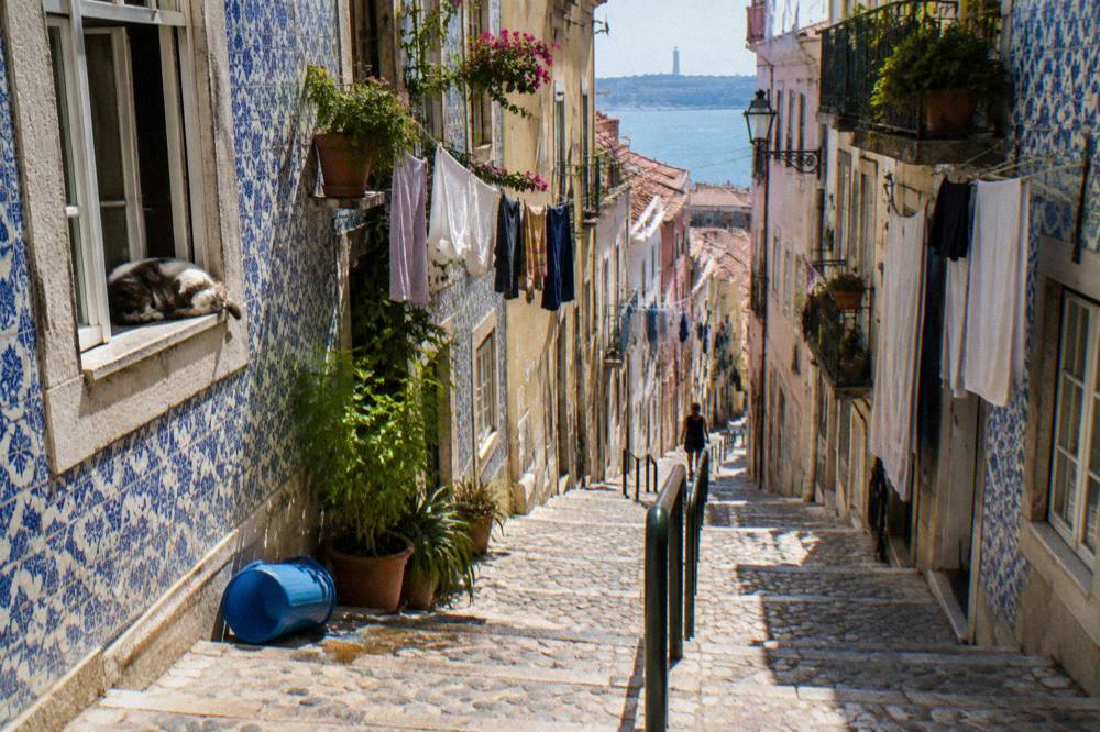 Narrow stepped street in Alfama with tiled facades and hanging laundry