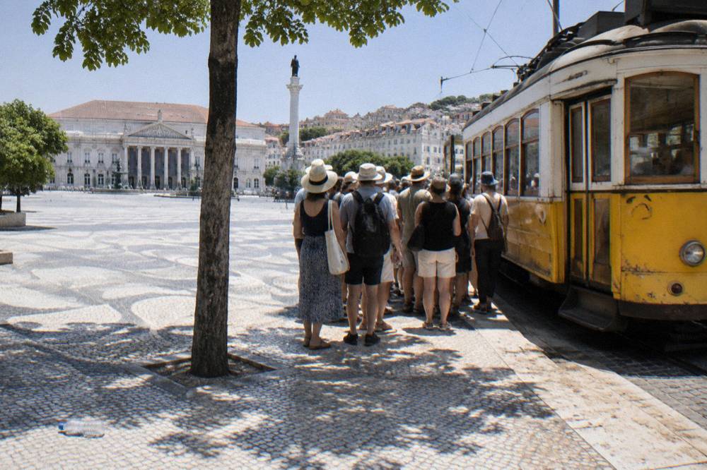 Crowd of visitors waiting at a tram stop beside a yellow heritage tram