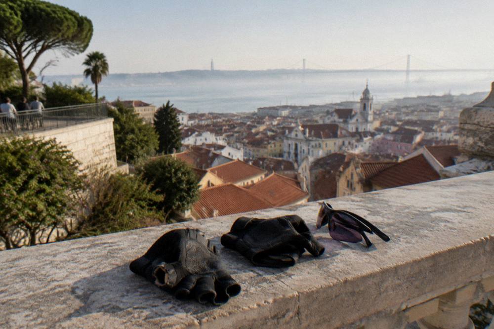 Electric bicycles parked at a Lisbon viewpoint overlooking rooftops and the river